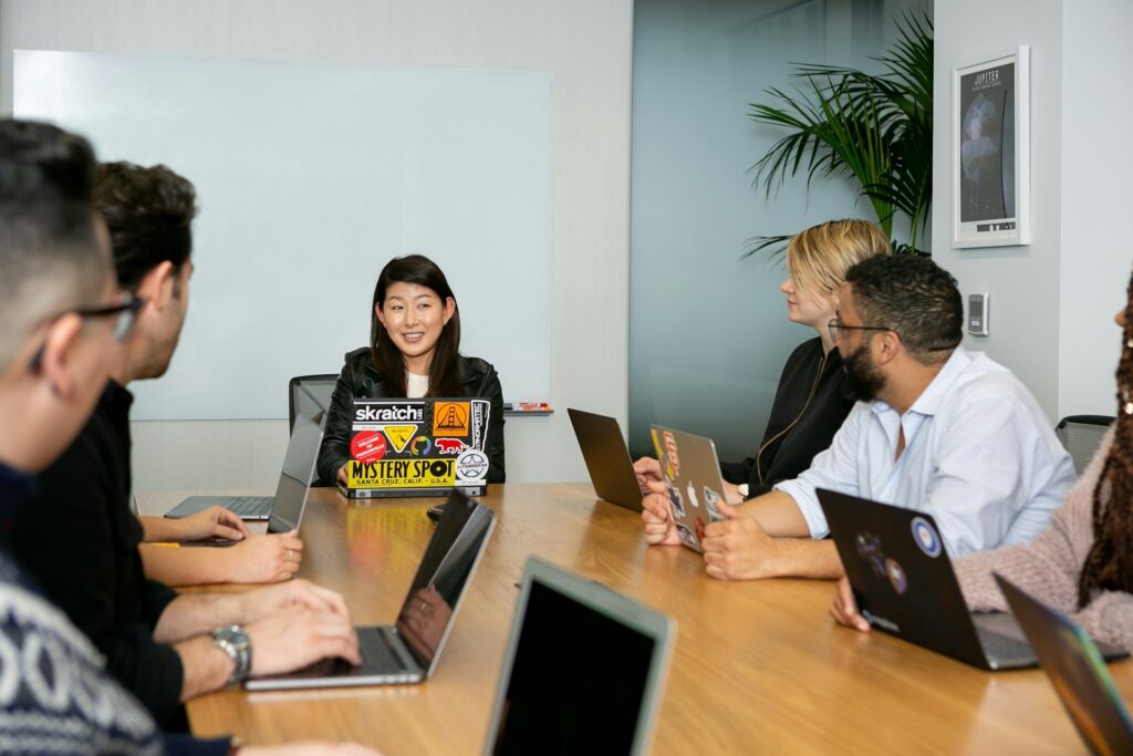 an image of people sitting on a table and talking to each other in Software development company